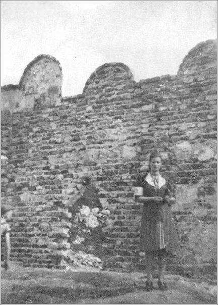 A Jewish girl stands next to the ghetto wall in Krakow